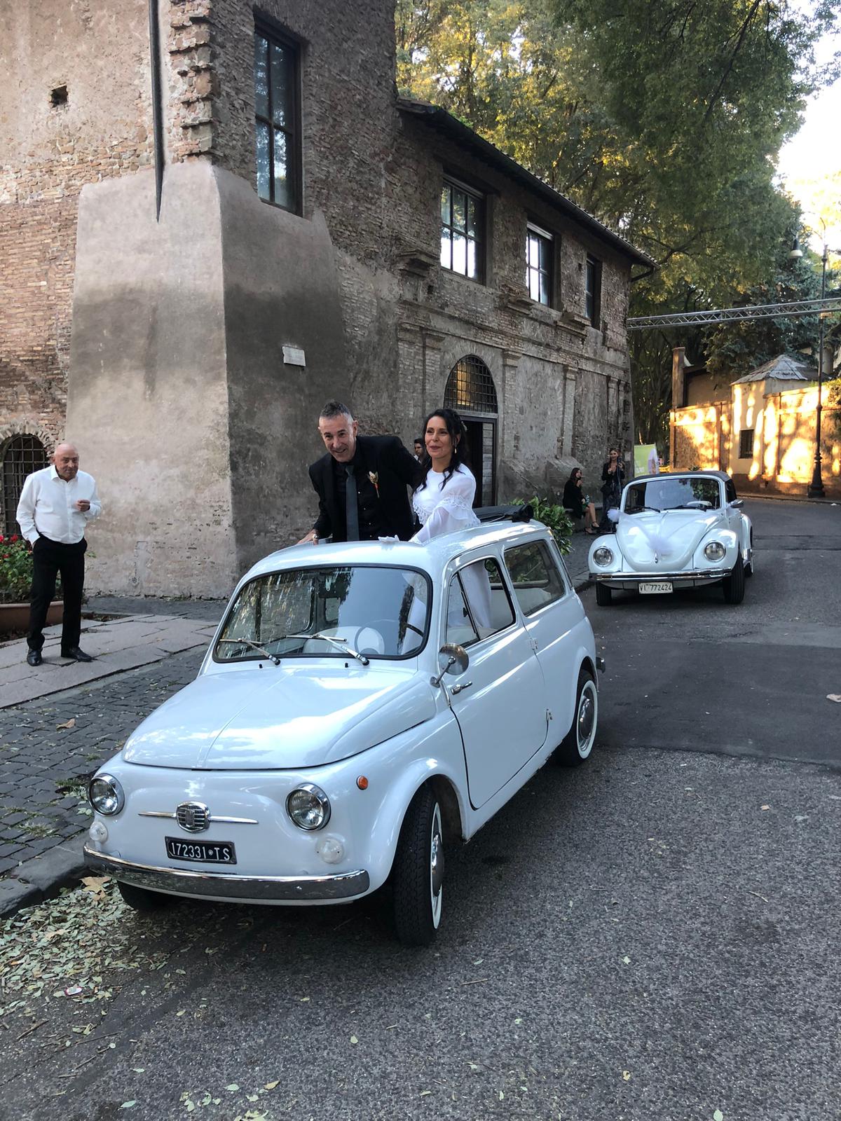 Bride and groom in a white vintage Fiat 500 convertible during a wedding in Rome