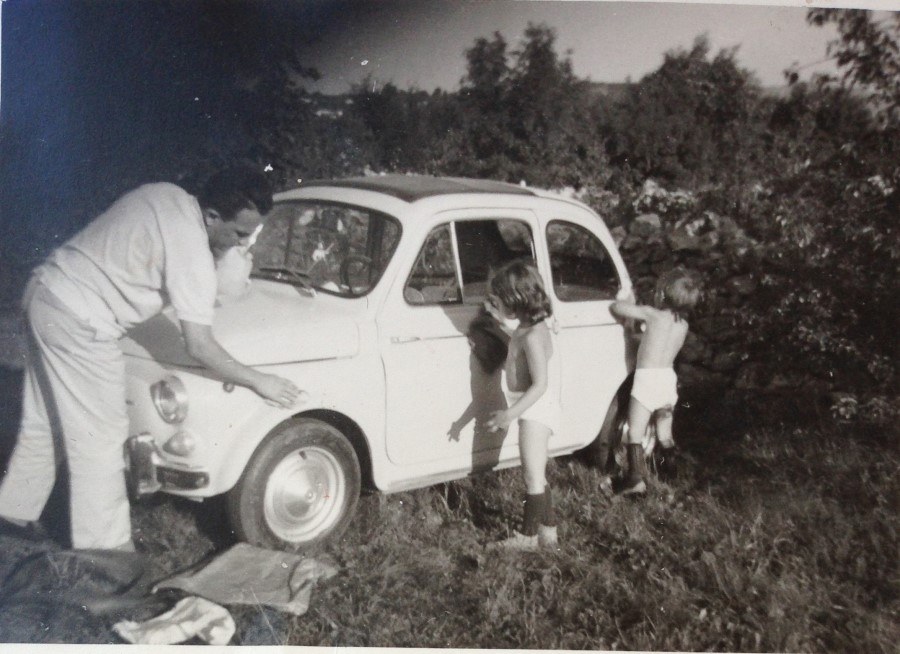Historical black and white photograph of a family washing a vintage Fiat 500
