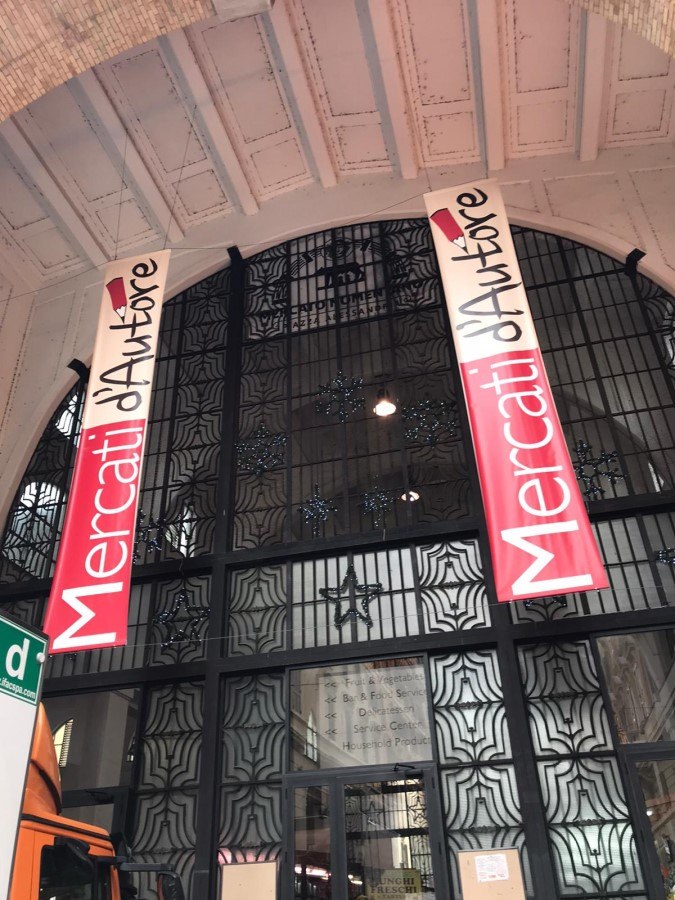 Roman market entrance with tall red banners reading Mercati d'Autore
